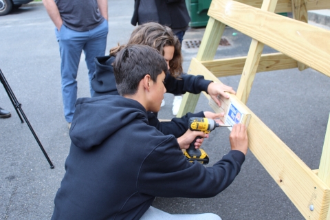 students affix plaque onto lifeguard stand